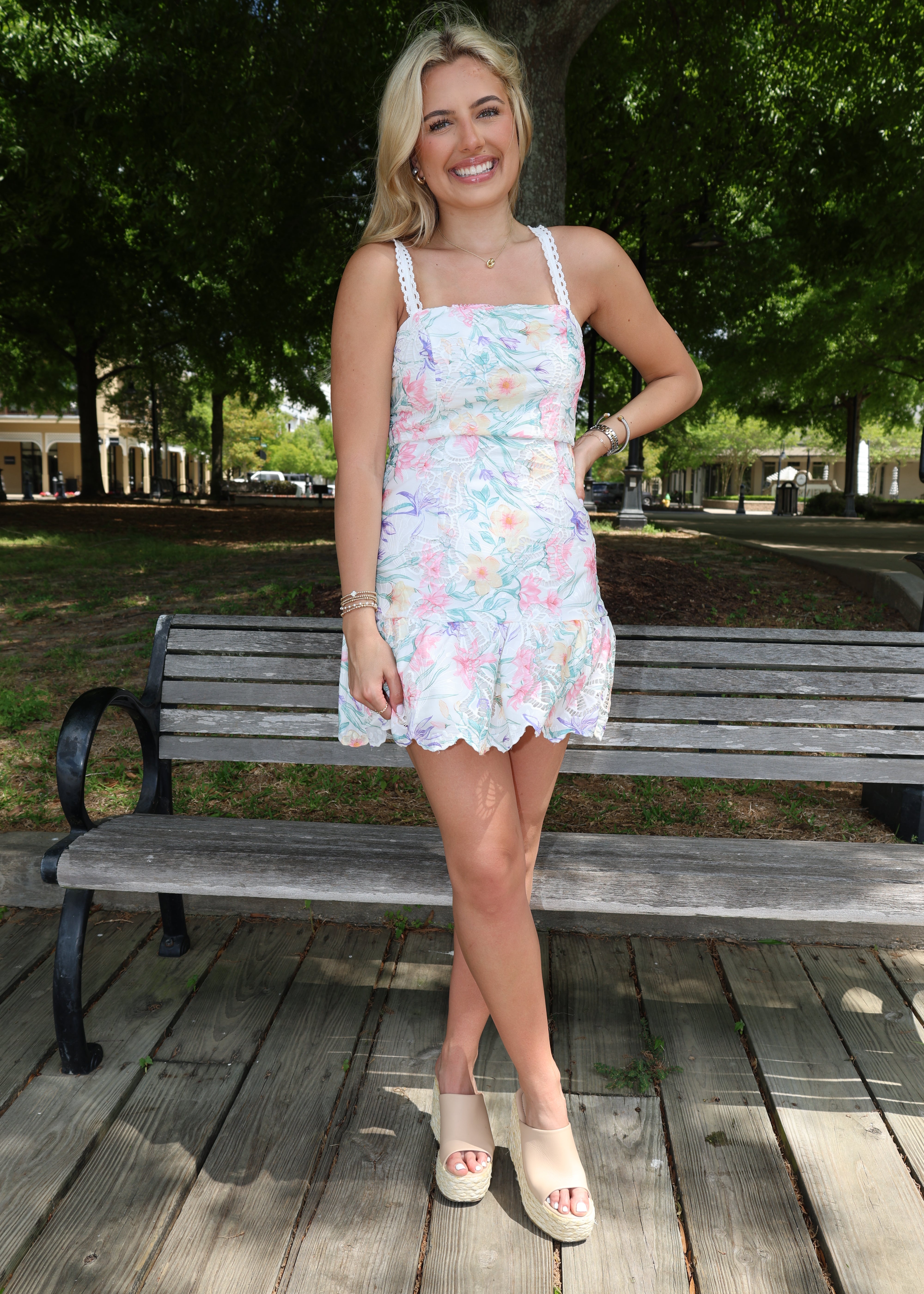 Woman in a floral dress standing on a wooden deck with trees in the background