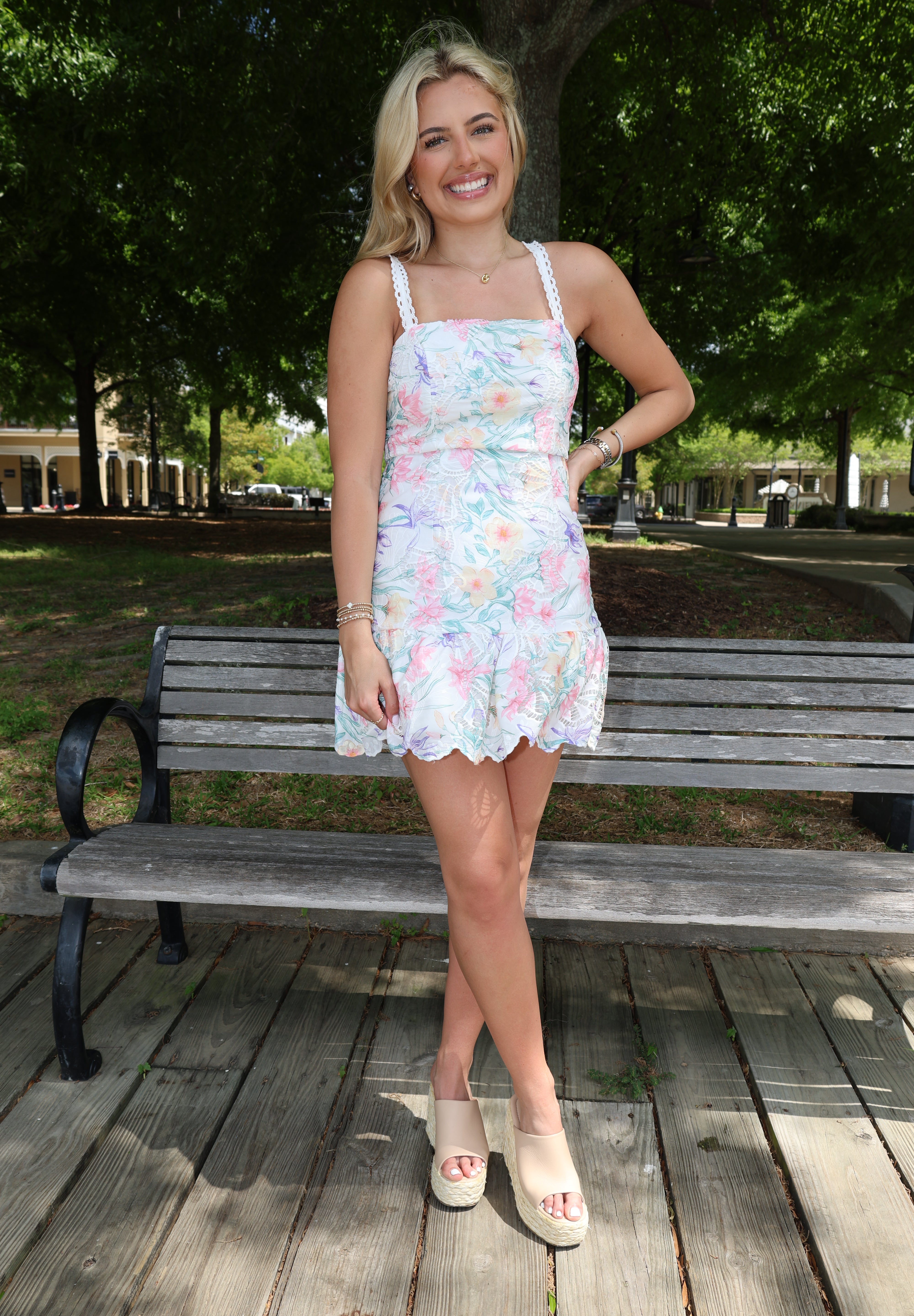 Woman in a floral dress standing on a wooden deck with trees in the background