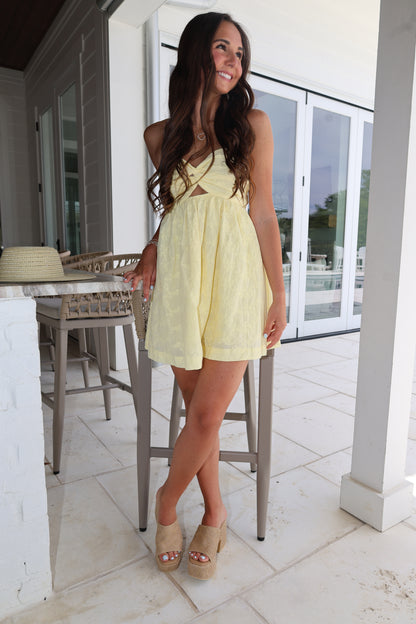 Woman in a yellow dress standing on a balcony with a white railing.