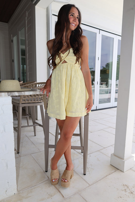 Woman in a yellow dress standing on a balcony with a white railing.