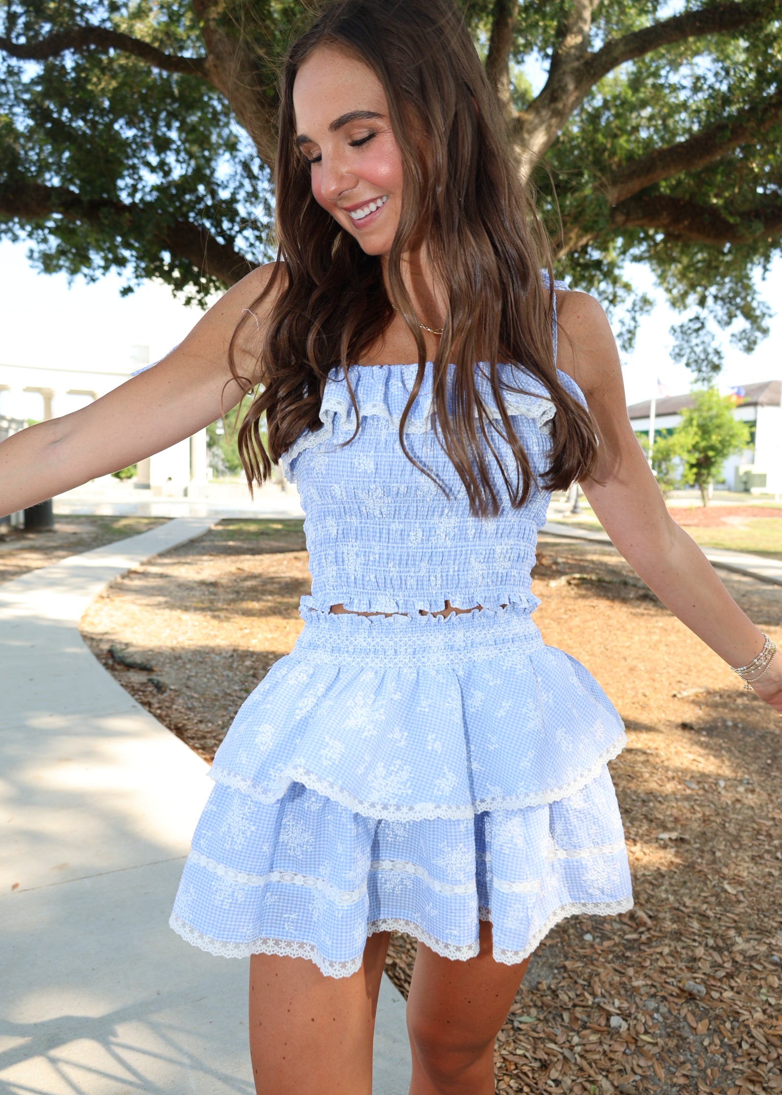 Woman wearing a light blue dress with ruffled sleeves and skirt, standing outdoors.
