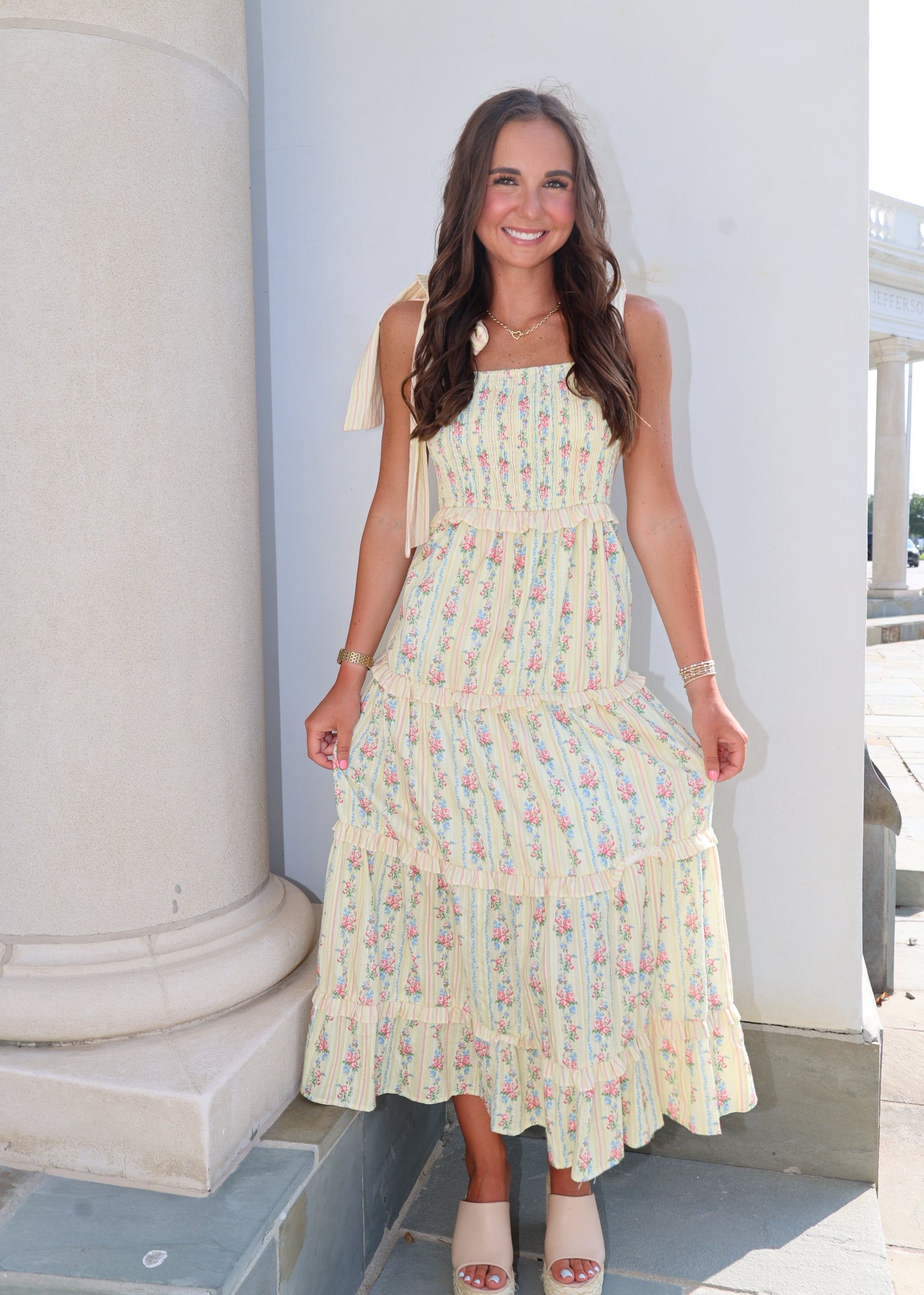 Woman wearing a pastel dress standing against a light blue wall.