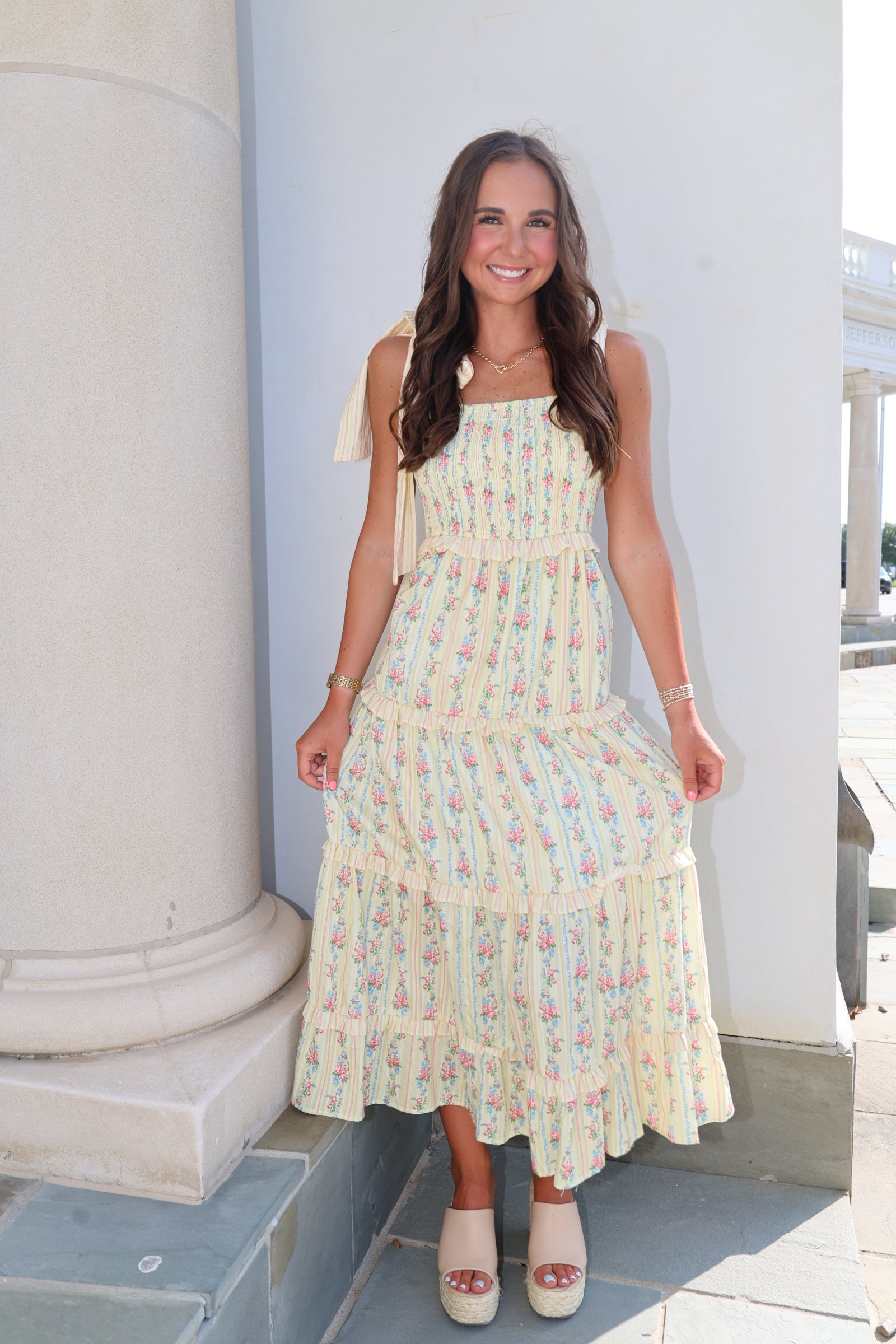Woman wearing a pastel dress standing against a light blue wall.