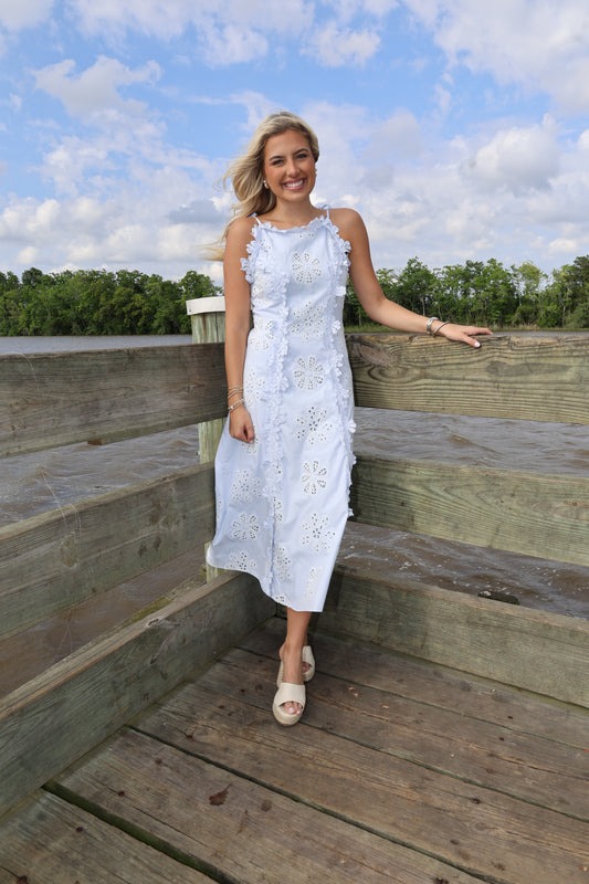 Woman in a white dress standing on wooden planks with a blue sky and clouds in the background