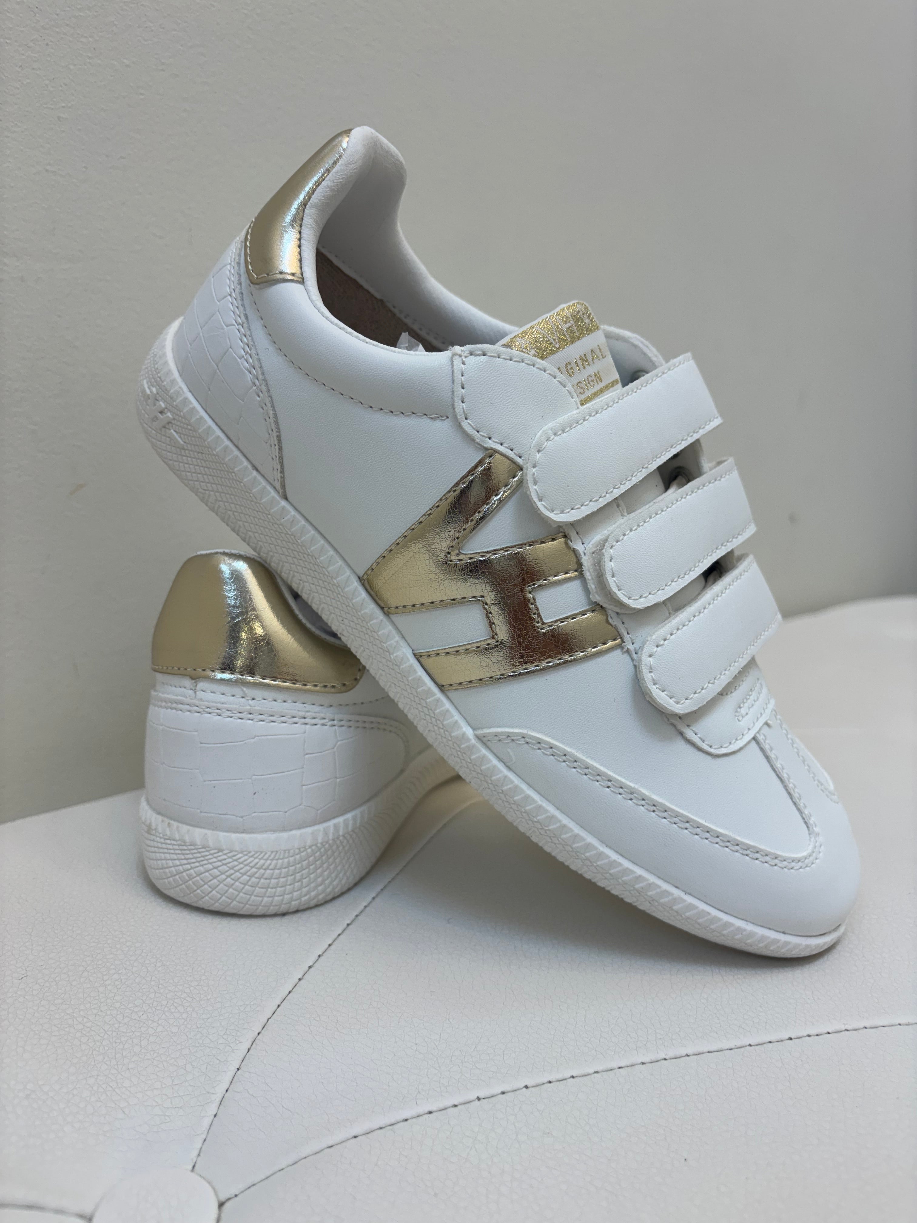White sneakers with gold accents on a light gray background