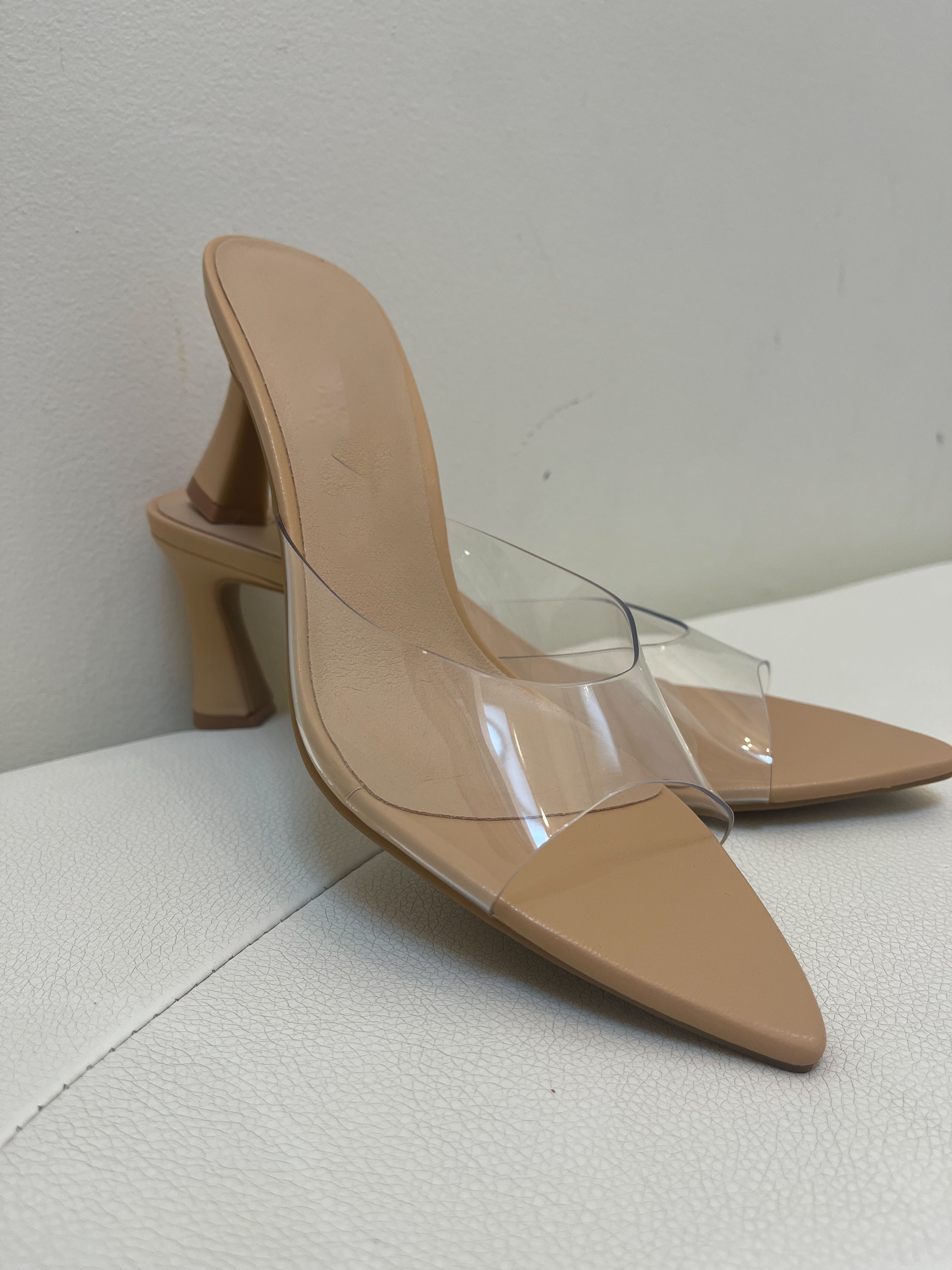 Beige high-heeled shoes with clear heel on a light gray surface
