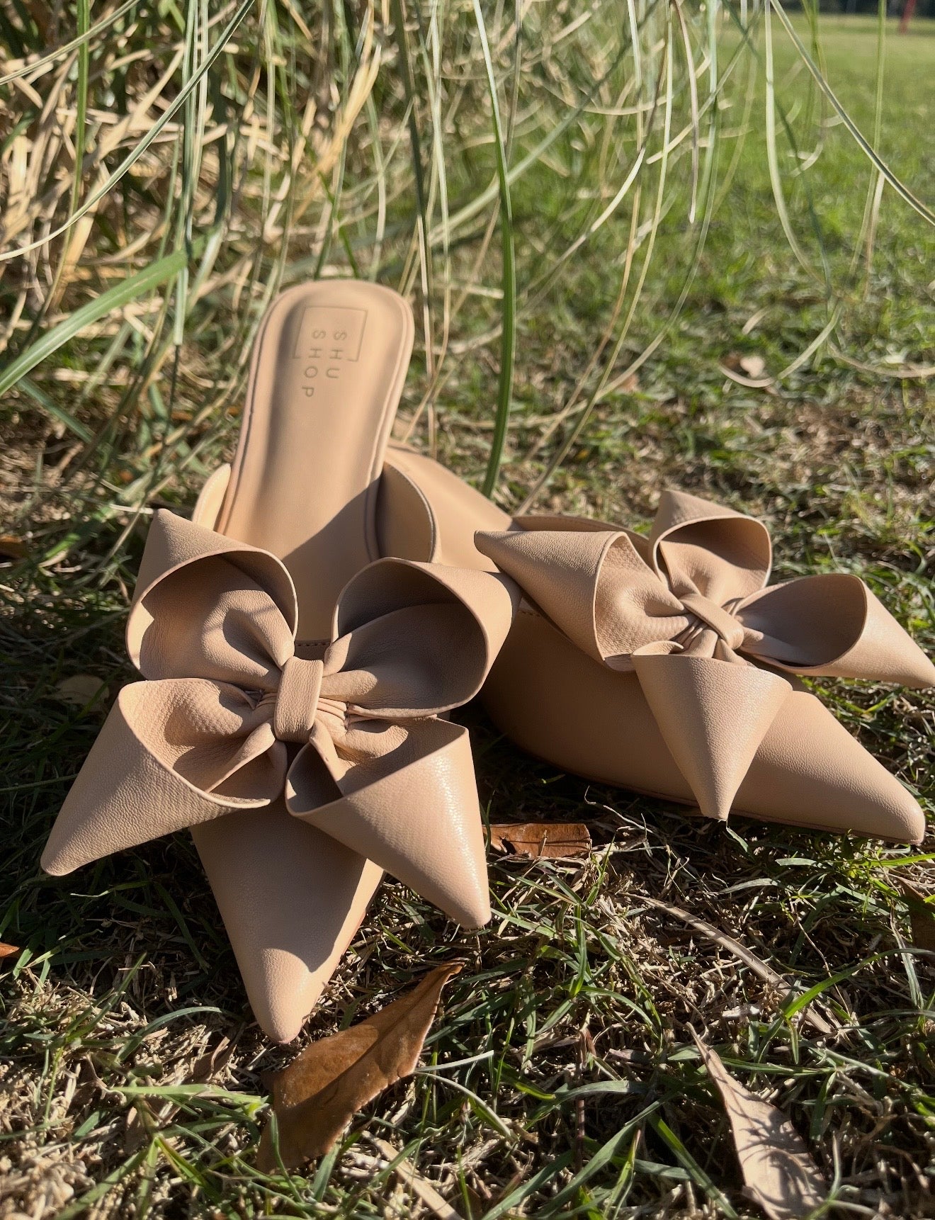 Pair of beige floral sandals on grass