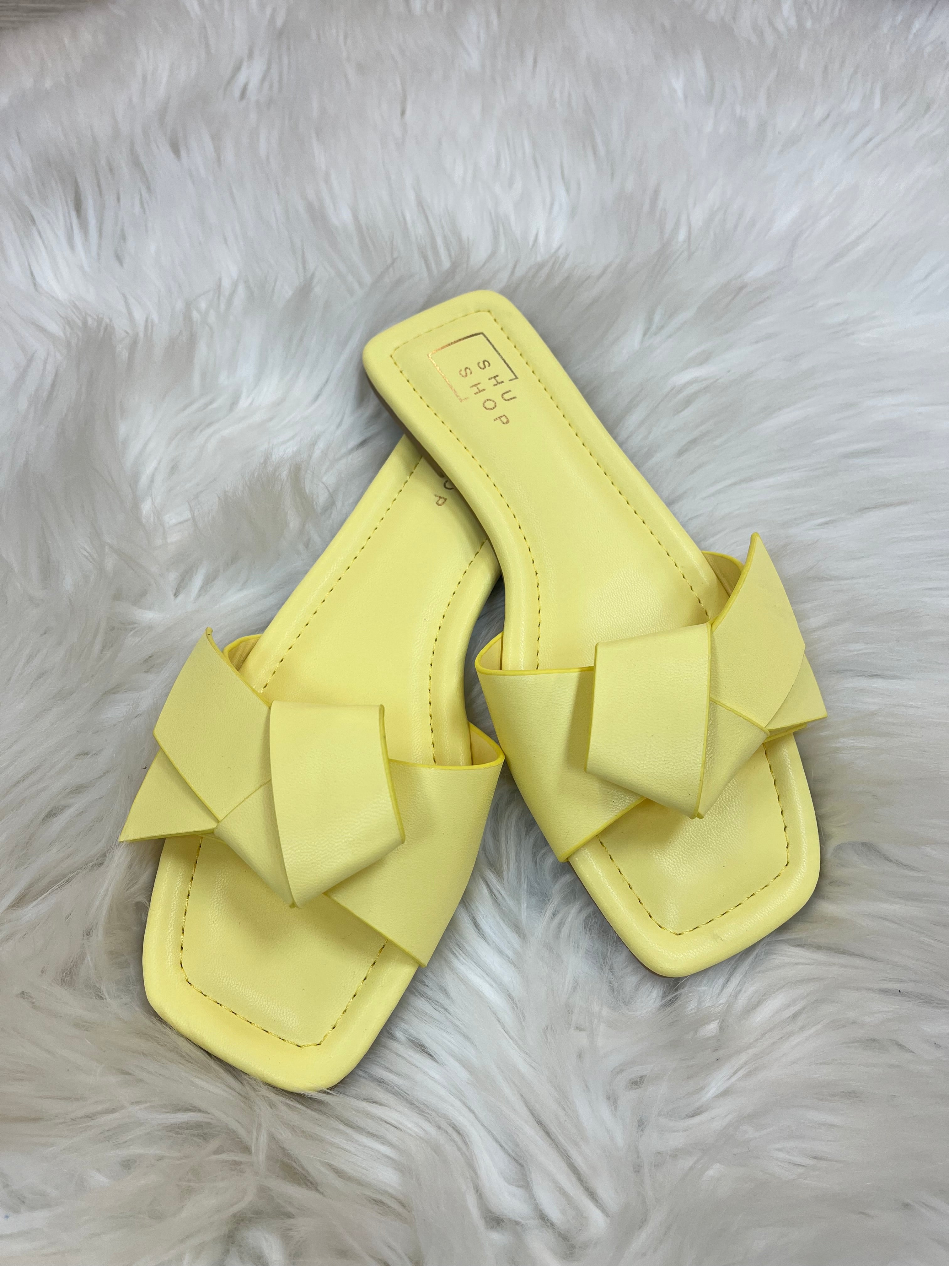 Yellow sandal with ruffle details on a fluffy white surface