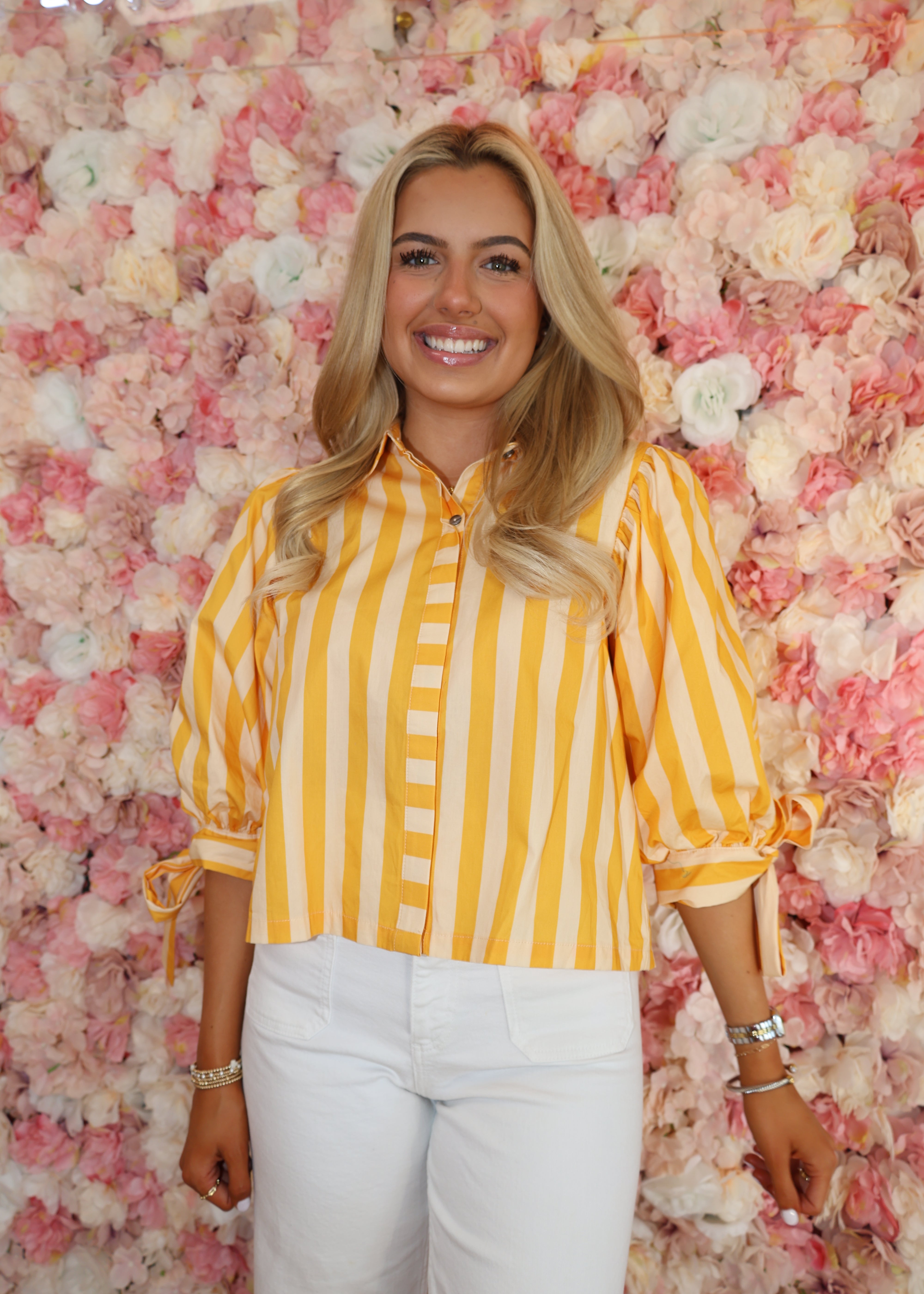 Woman in a yellow striped shirt lying on a pink floral surface with '2018' text.