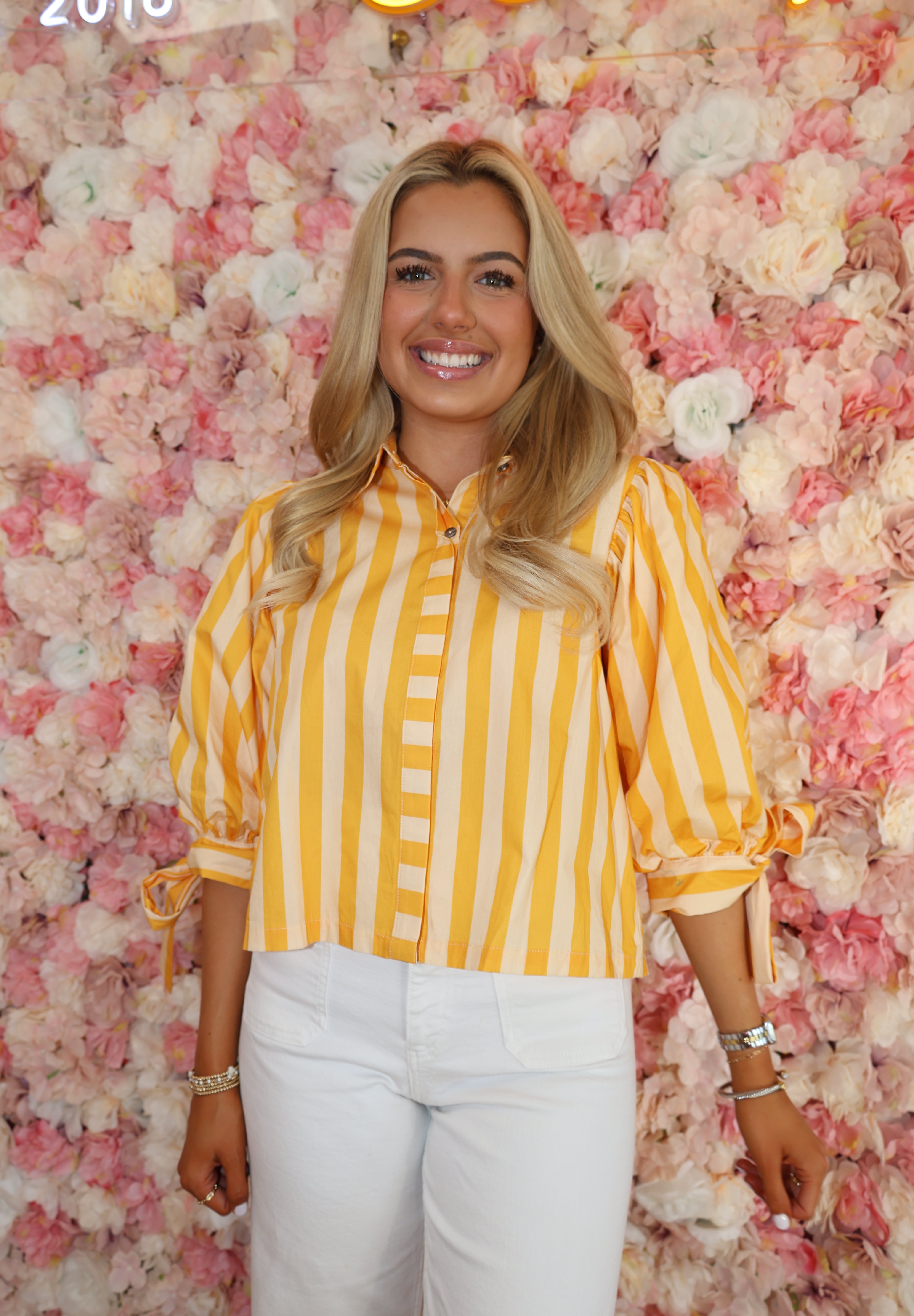 Woman in a yellow striped shirt lying on a pink floral surface with '2018' text.