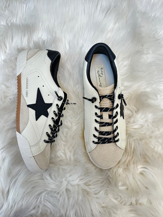Pair of white sneakers with black stars on a fluffy white surface