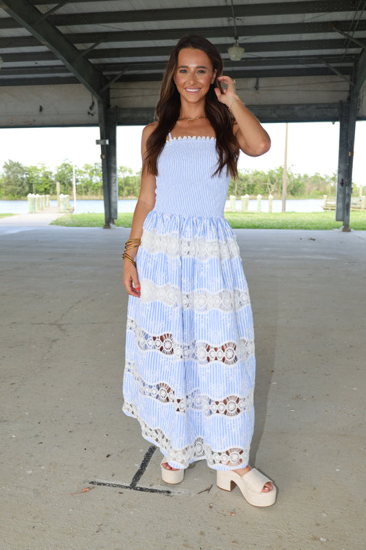 Woman wearing a light blue dress with white lace details outdoors.