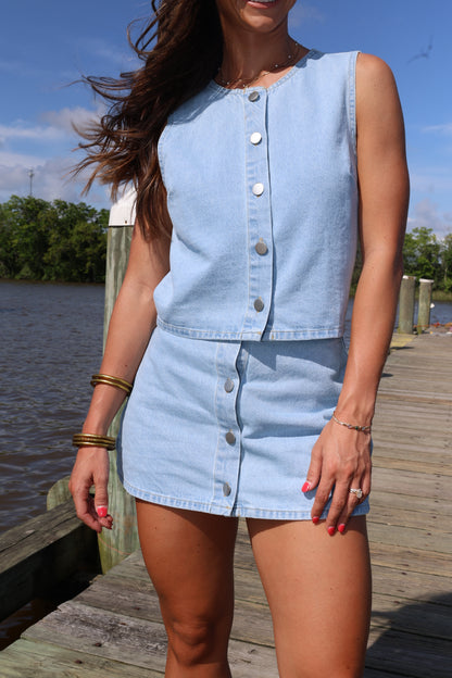 Person wearing a light blue denim dress with a blurred background