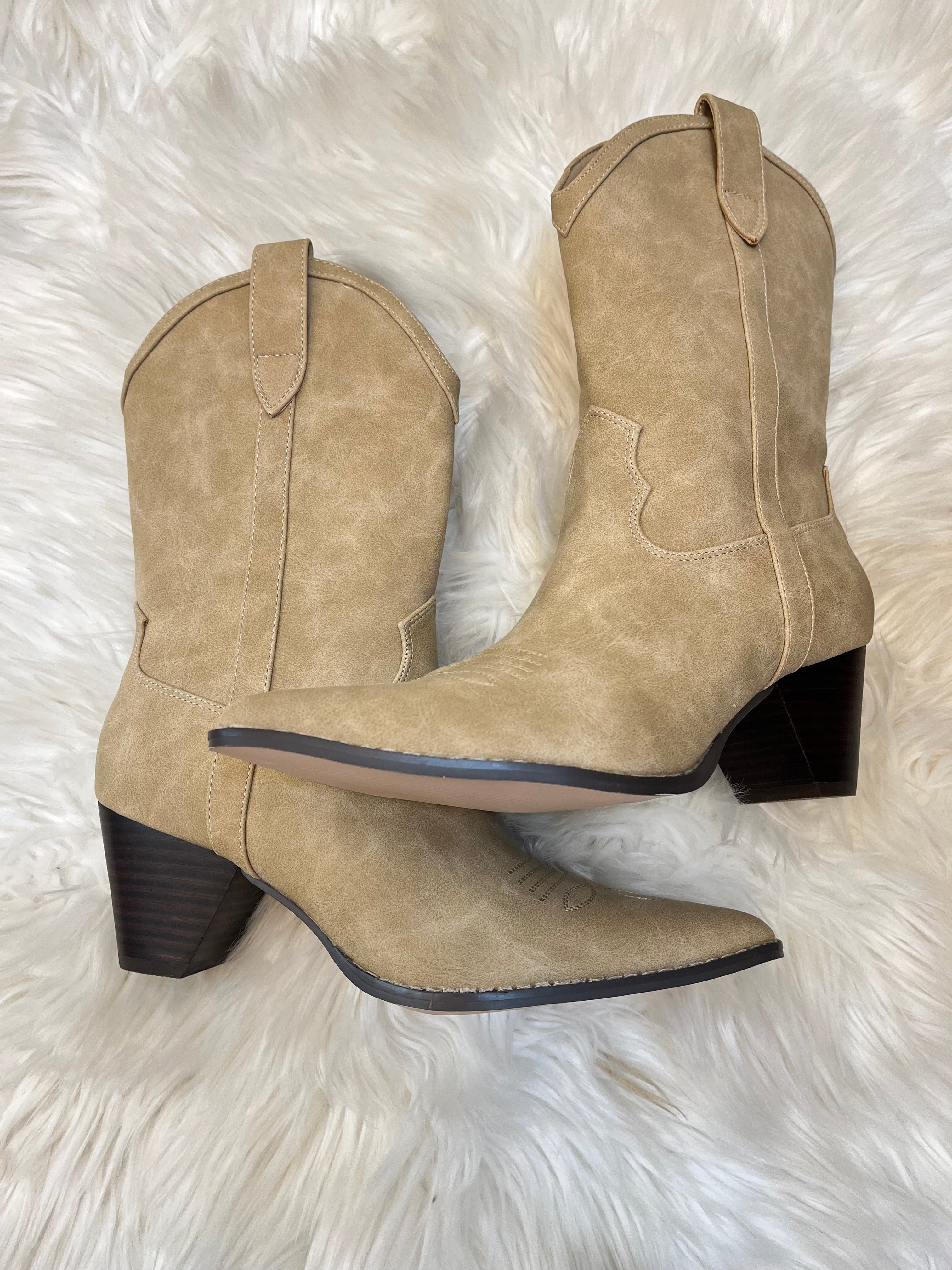 Pair of beige ankle boots on a white fluffy surface