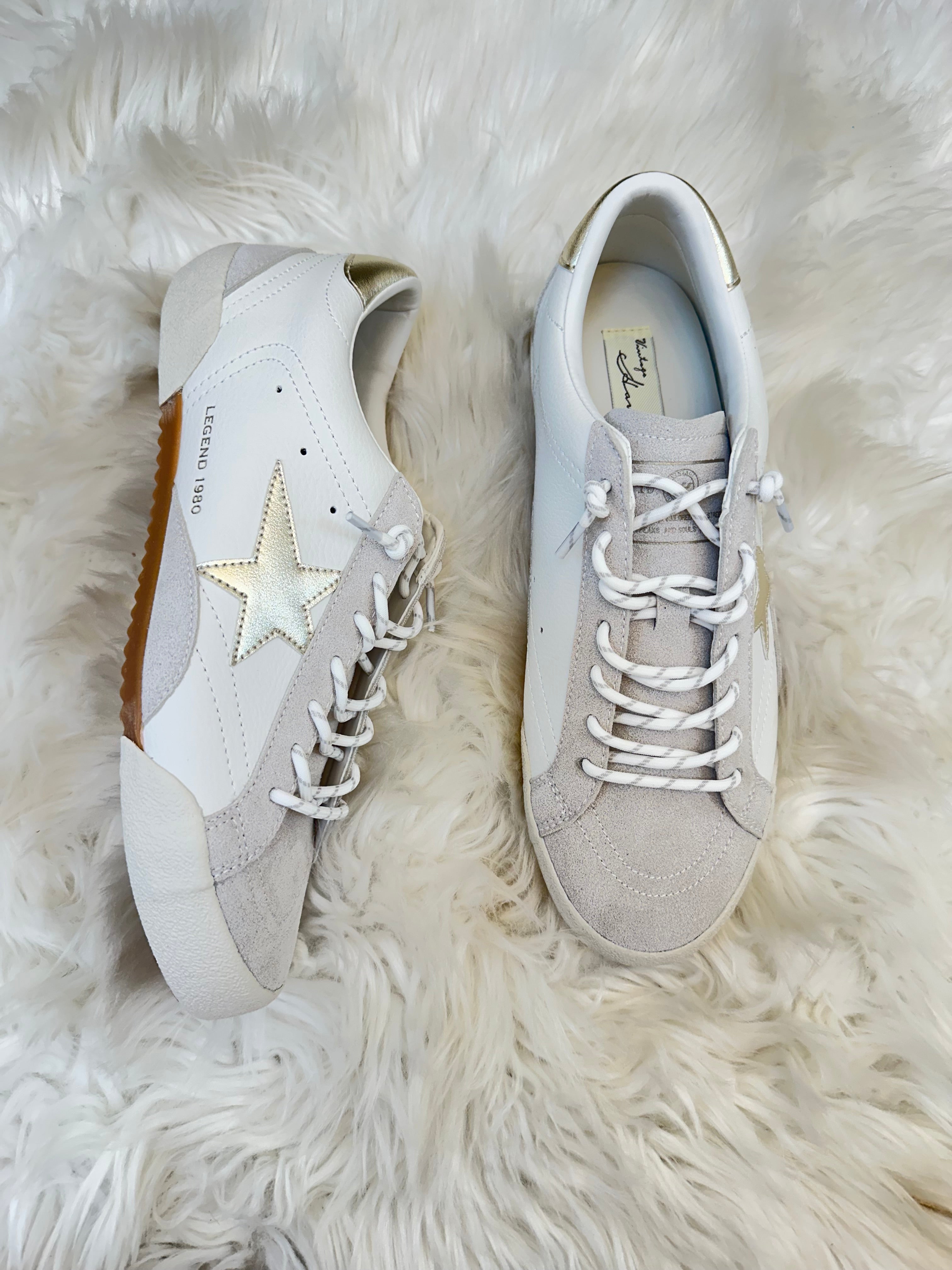 Pair of light gray sneakers with a star design on a white fur surface
