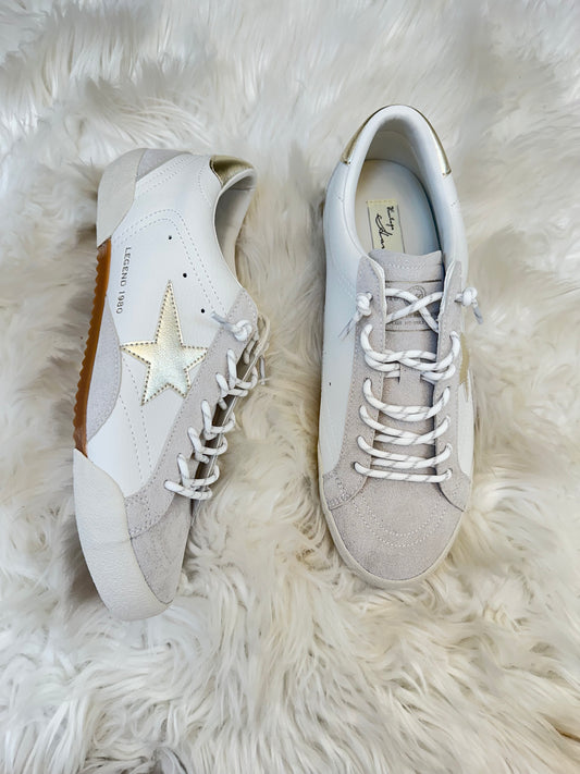 Pair of light gray sneakers with a star design on a white fur surface