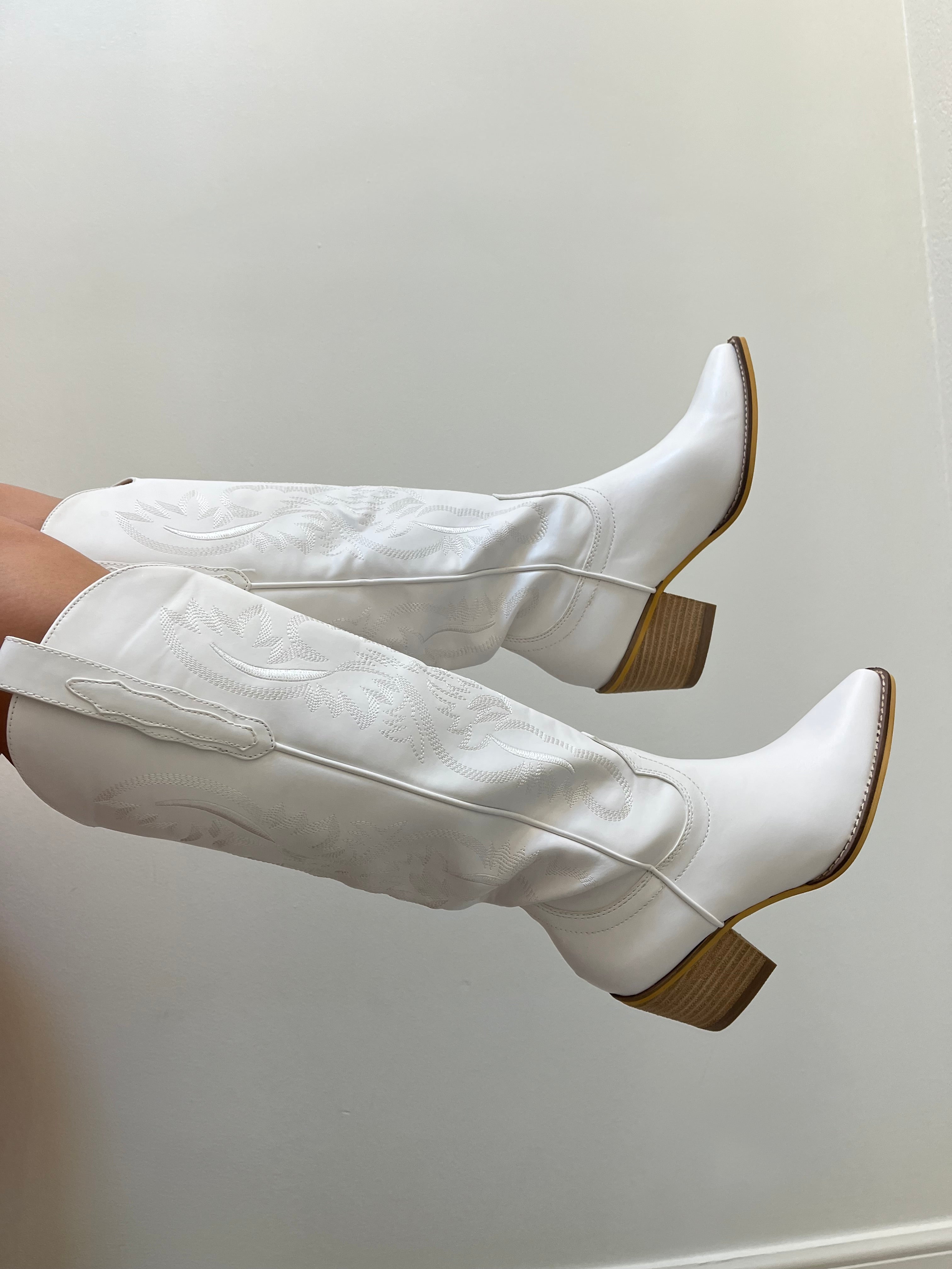 White knee-high boots with brown soles on a white background