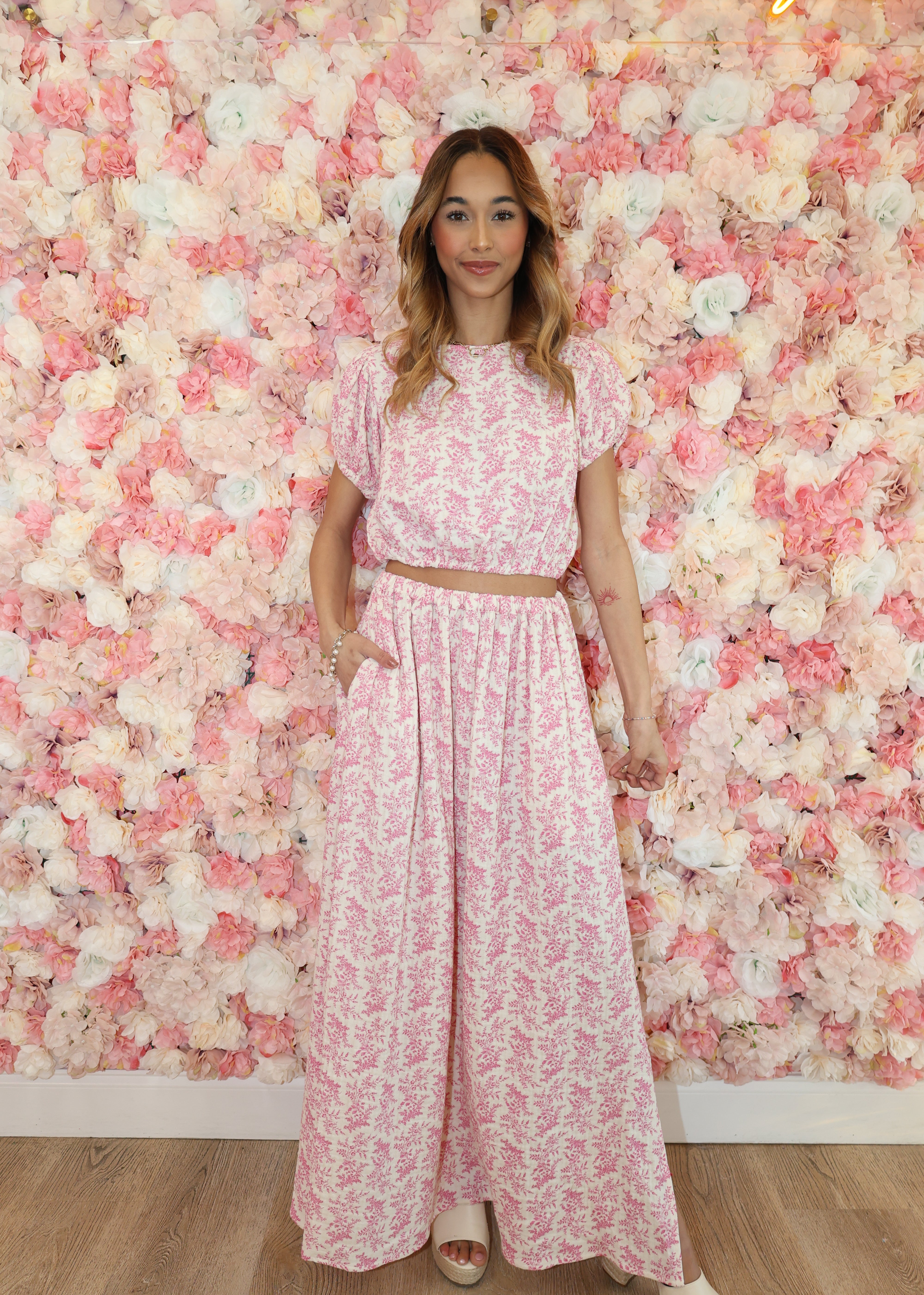 Woman in a pink floral dress lying on a bed of pink flowers.