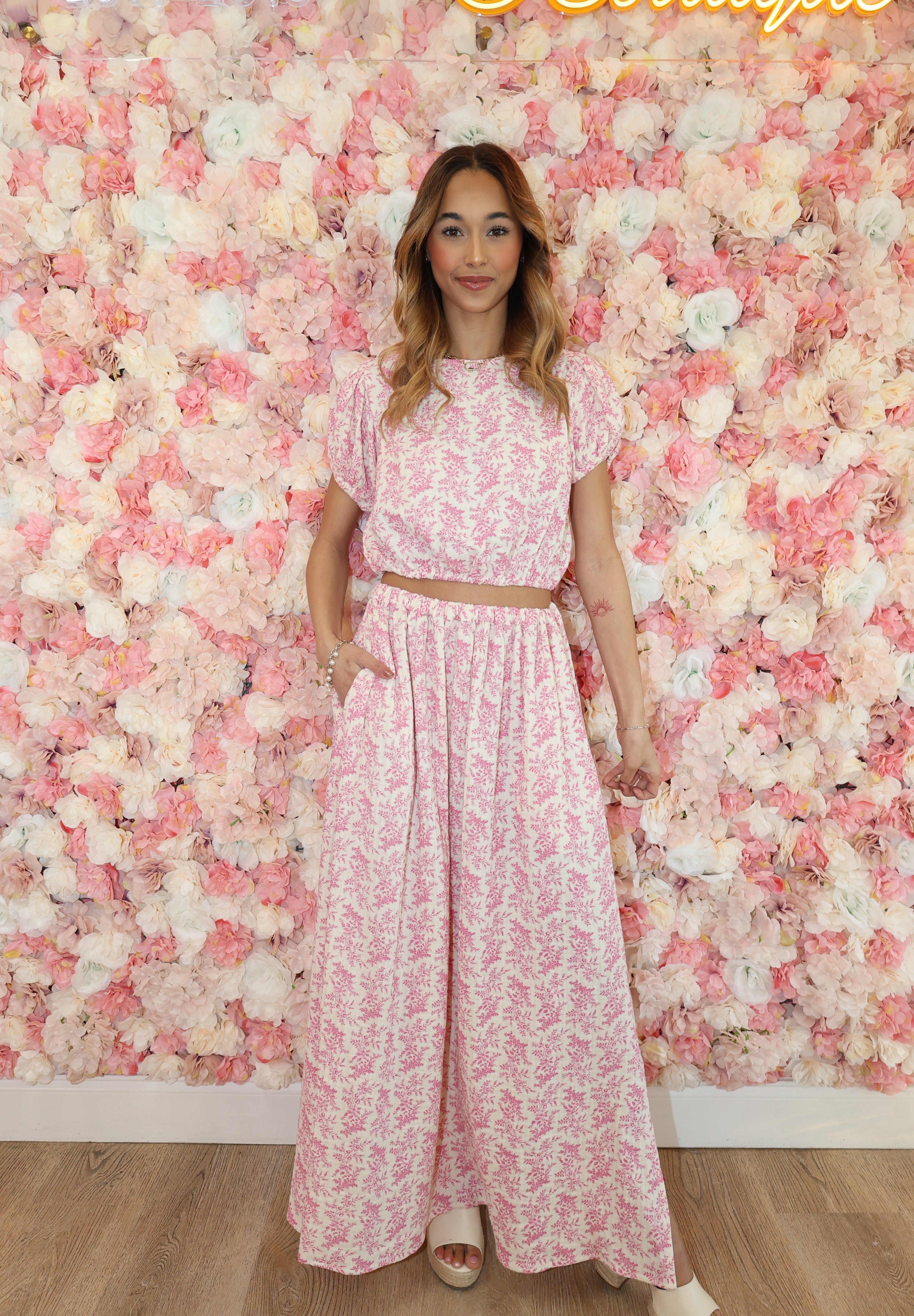 Woman in a pink floral dress lying on a bed of pink flowers.