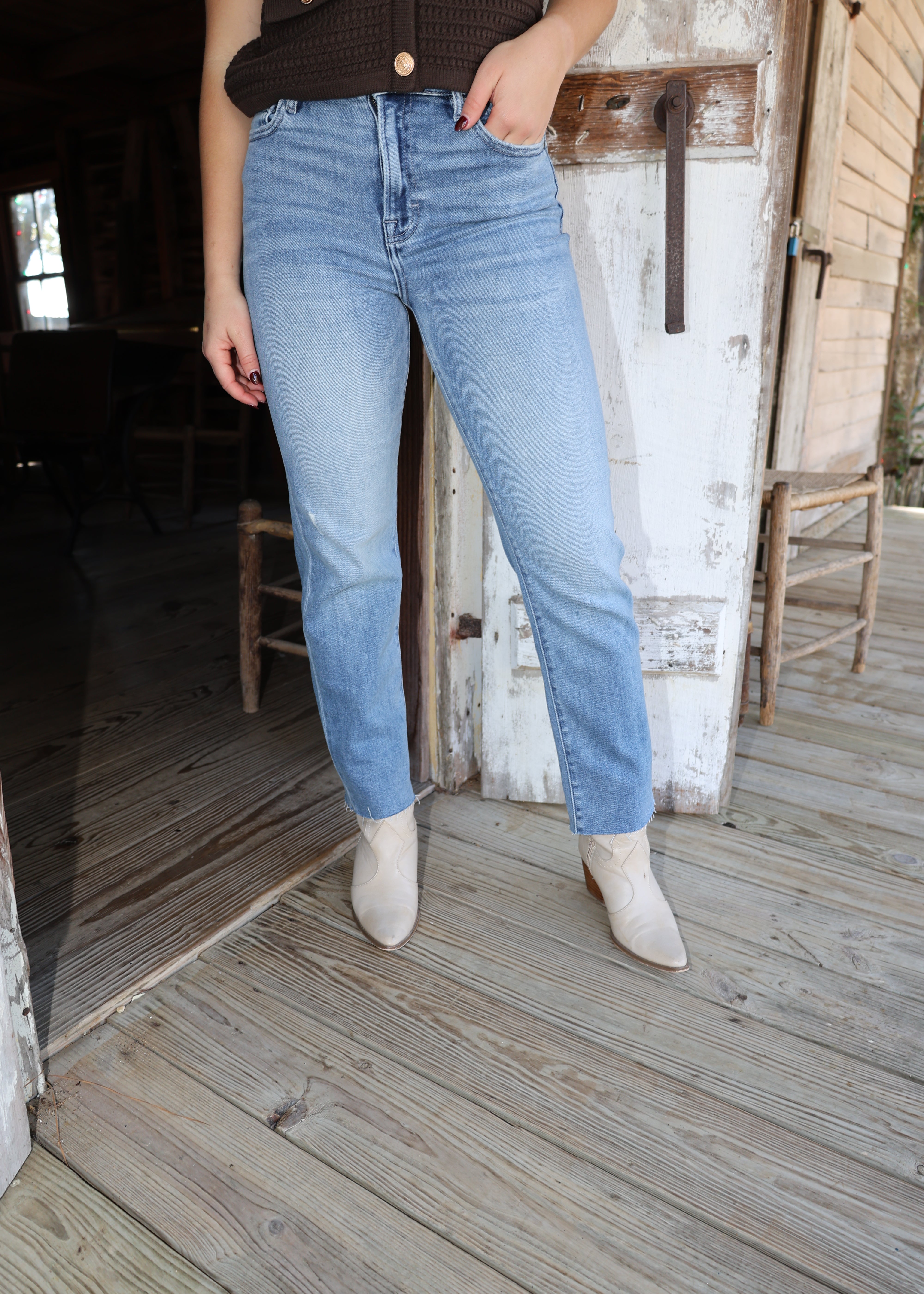 Person wearing light blue jeans sitting on a wooden bench indoors.