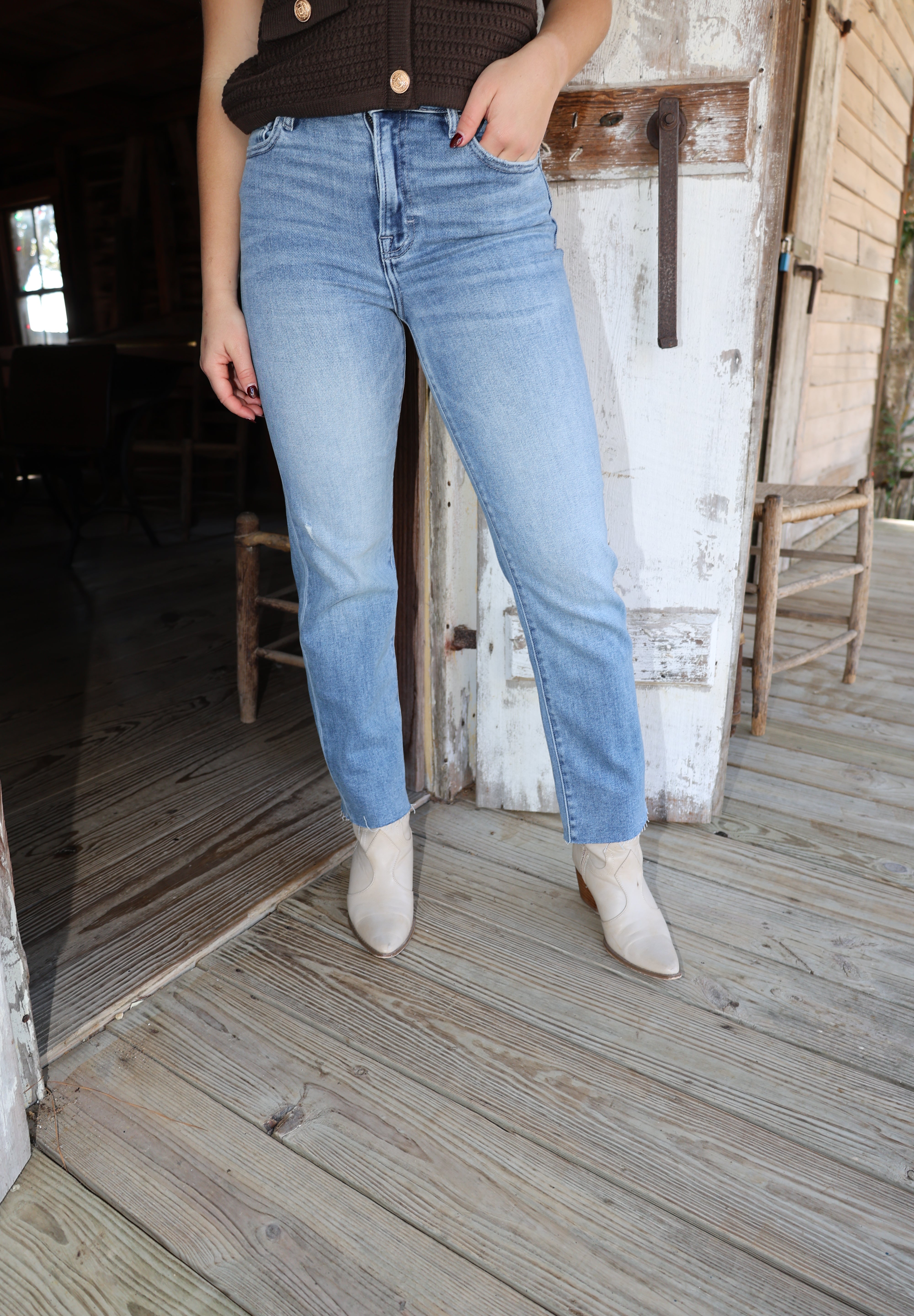 Person wearing light blue jeans sitting on a wooden bench indoors.