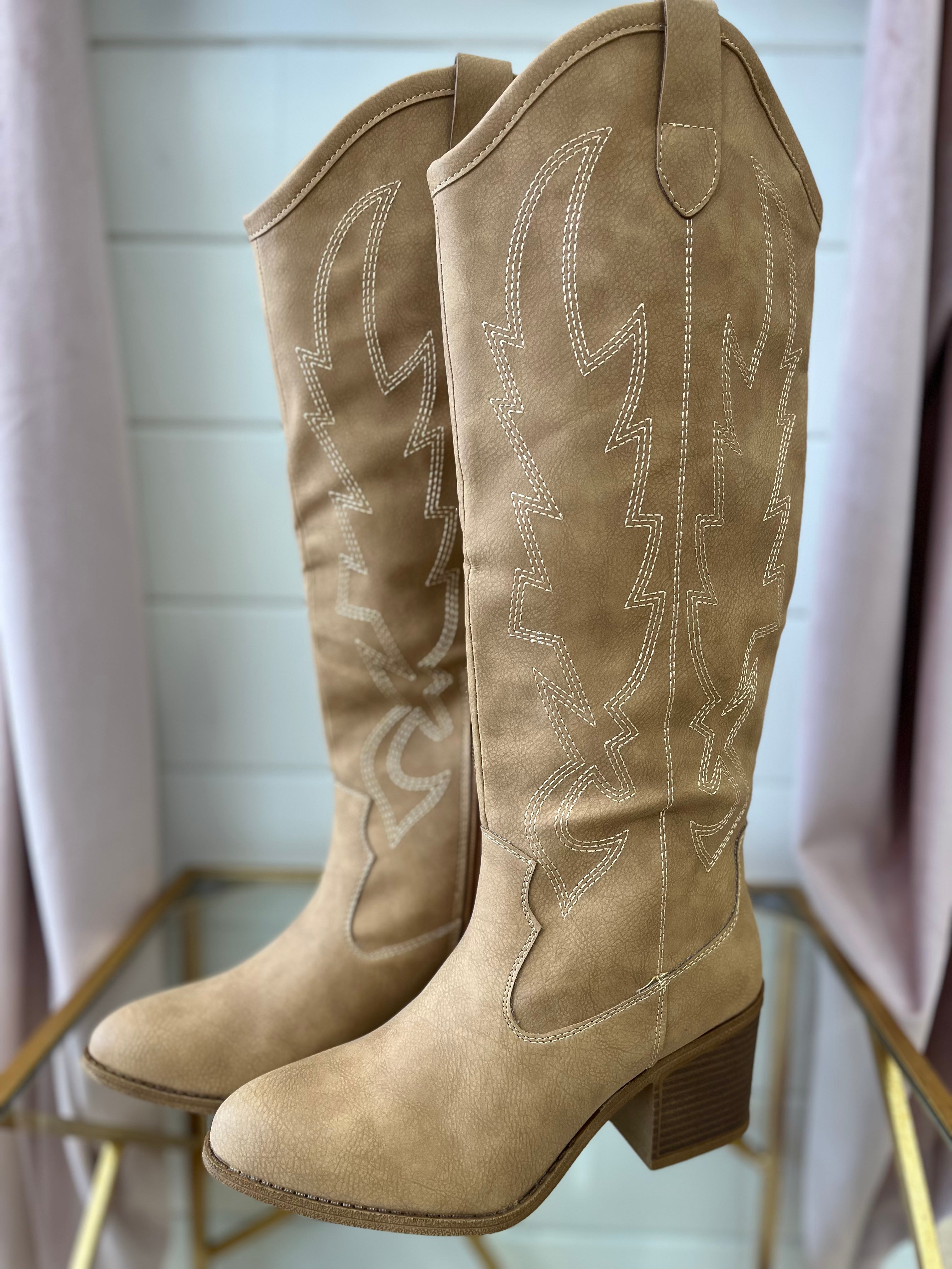 A pair of beige knee-high boots with a low heel, displayed against a neutral background.